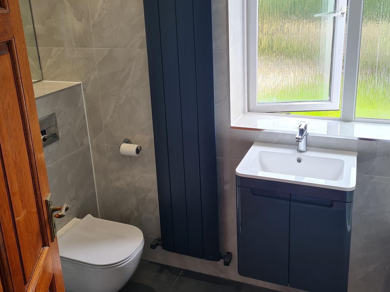Ensuite with a tall navy vertical radiator, navy vanity unit and concealed-cistern WC